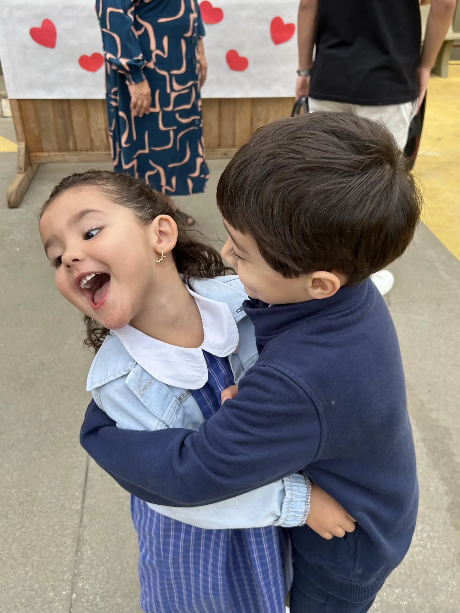 Dois alunos se abraçando e rindo no pátio do colégio
