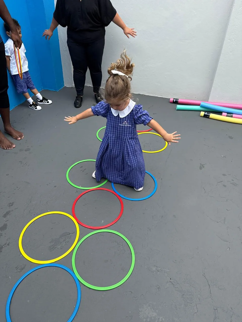 Criança da Educação Infantil em brincadeira dirigida com arcos coloridos