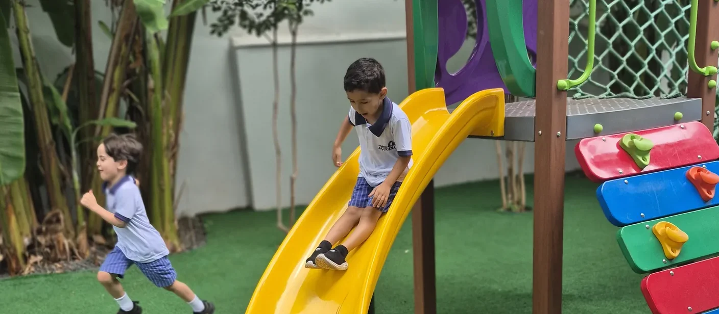 Crianças da Educação Infantil brincando no escorregador do parquinho