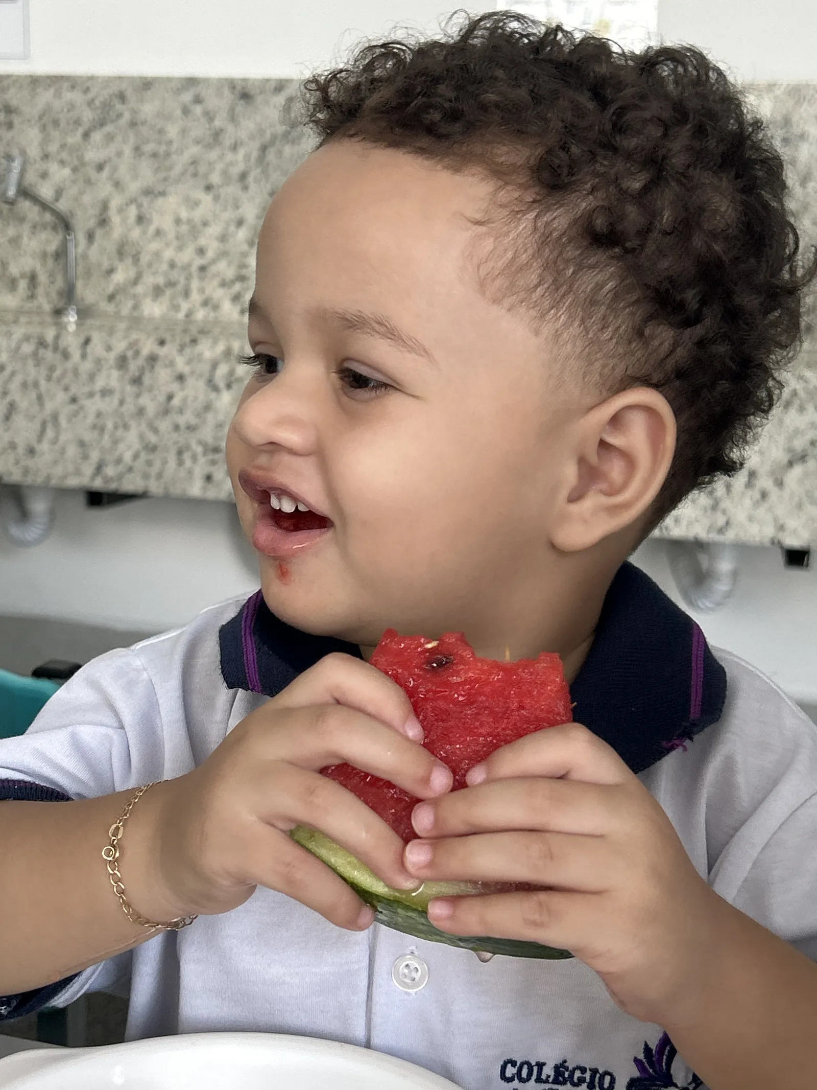 Aluno sorrindo enquanto come melancia na hora do lanche