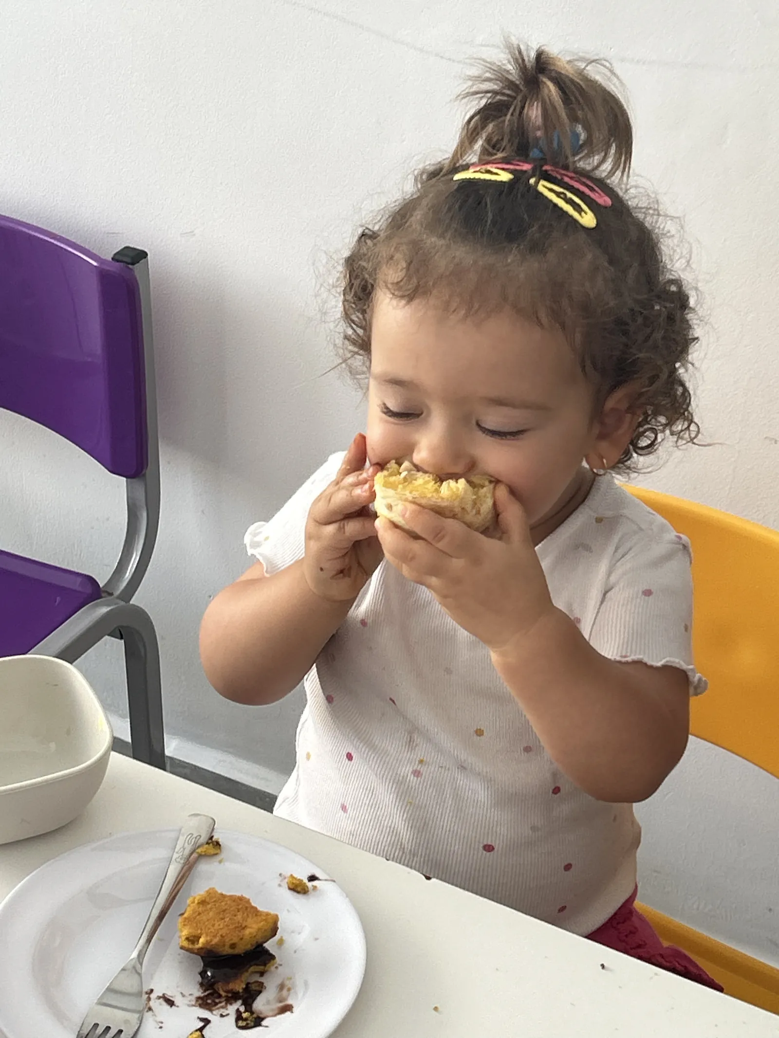Criança saboreando o lanche na mesa do refeitório