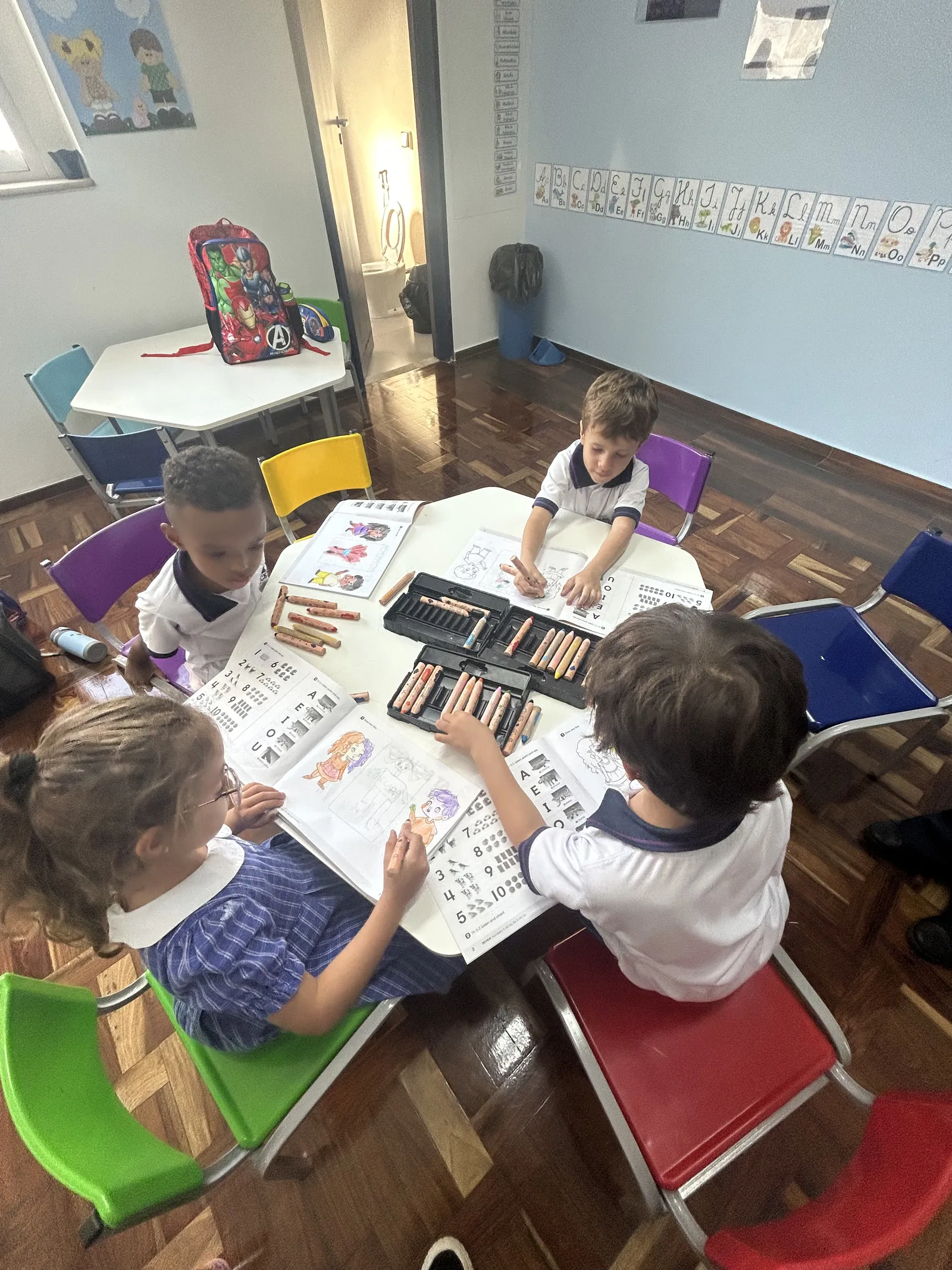 Alunos estudando com livros e lápis de cor em sala de aula